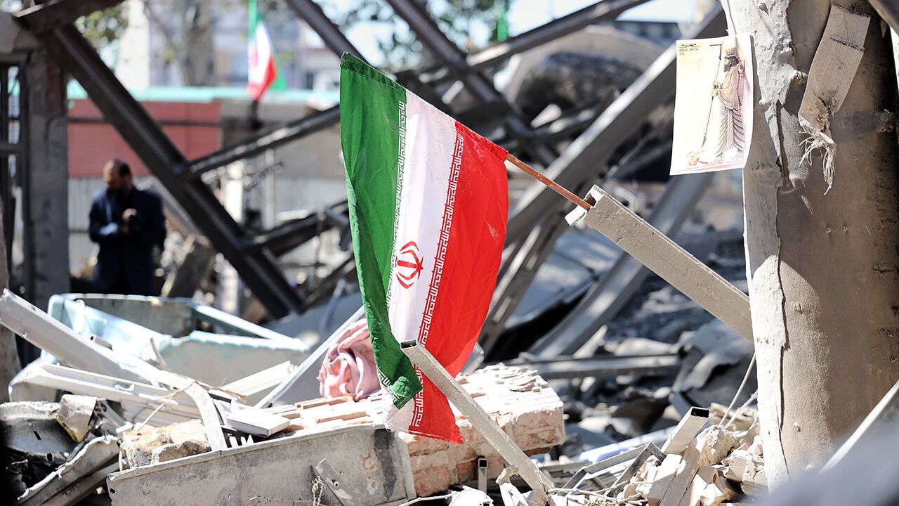 An Iranian national flag is placed on the debris of a damaged building after an airstrike in Tehran
