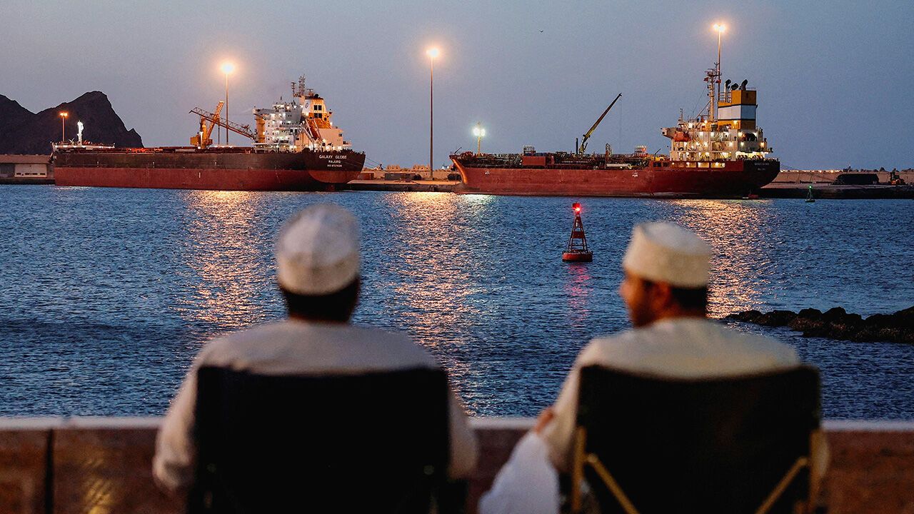 Two men look across the Strait of Hormuz
