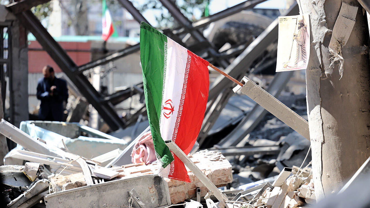 An Iranian national flag is placed on the debris of a damaged building after an airstrike in Tehran