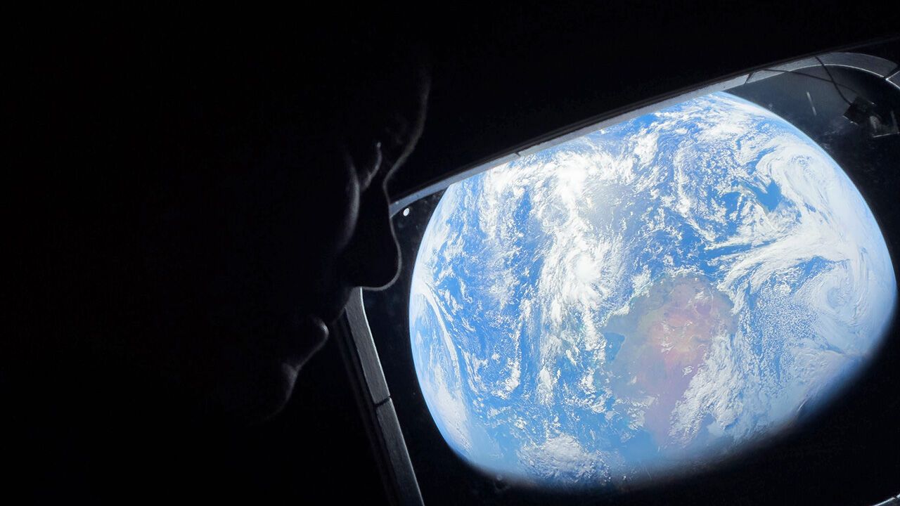 Commander Reid Wiseman peers out of one of the Orion spacecraft's main cabin windows, looking back at Earth
